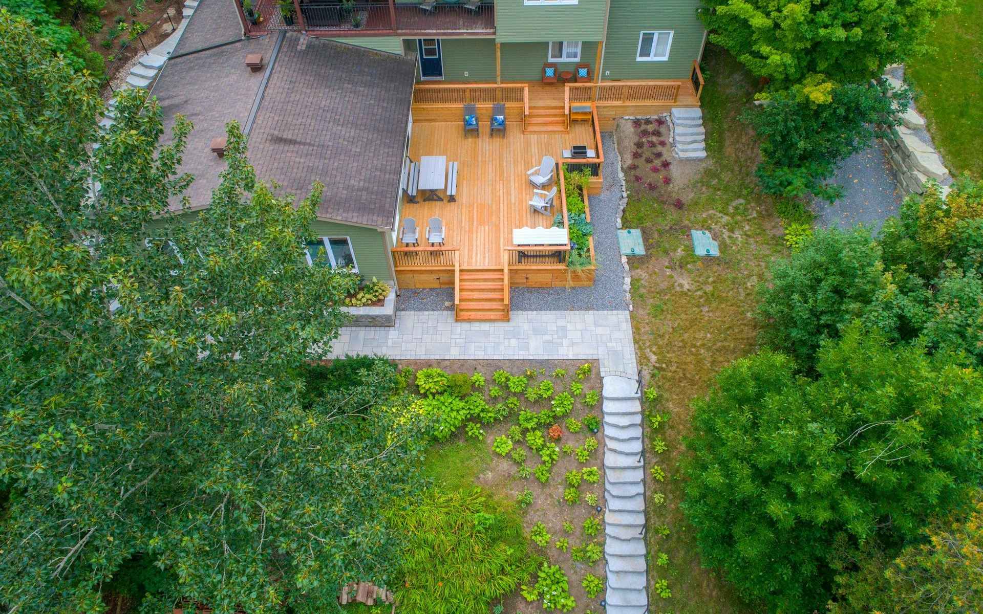 Jardin vu de dessus : terrasse en bois, allée et massifs